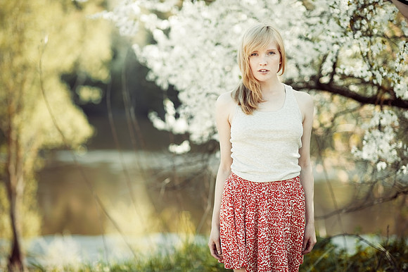 Young woman standing in a summer park near a lake